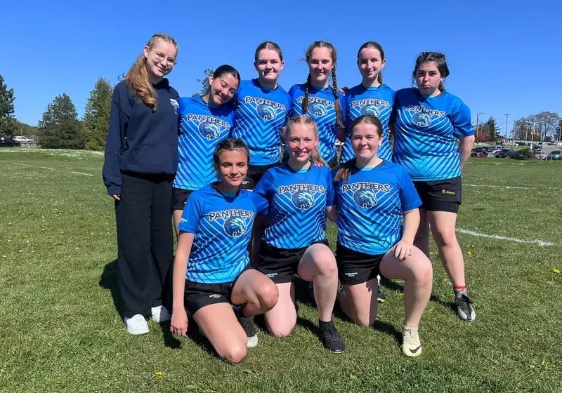 Gruppe von Schülerinnen im Fußballtrikot auf dem Spielfeld