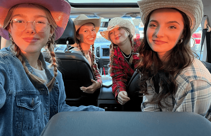 vier Schülerinnen im Auto mit einem Cowboy Hut