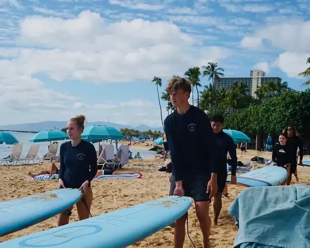 zwei Schülerinnen mit Surfbrettern am Strand